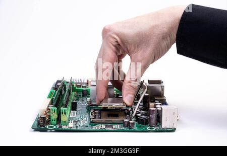 Engineer repairman holding hands in black gloves chip processor, CPU to insert into the socket of the computer motherboard. The concept of technology Stock Photo
