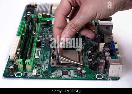 Engineer repairman holding hands in black gloves chip processor, CPU to insert into the socket of the computer motherboard. The concept of technology Stock Photo