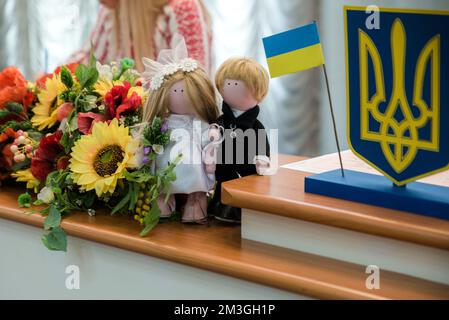 Ukrainian flag and coat of arms with fabric with texture of pixeled camouflage. Cloth with camo pattern in grey and green pixel shapes with Ukrainian Stock Photo