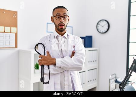 African american doctor man holding stethoscope at the clinic clueless and confused expression. doubt concept. Stock Photo