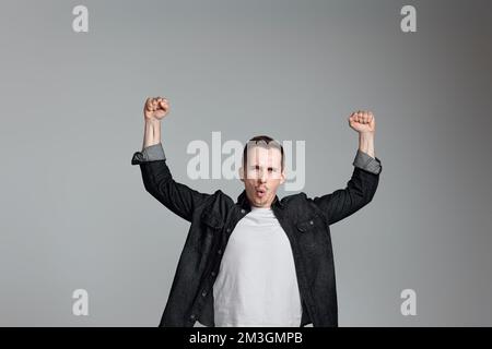 amazed man celebrating victory on gray background. Stock Photo