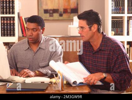 Two younger men working on a computer in home office Stock Photo