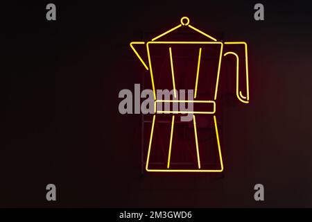 Yellow neon signage in the form of a Moka pot coffee maker against a black wall Stock Photo