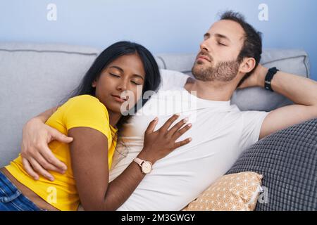 Man and woman interracial couple lying on sofa sleeping at home Stock Photo