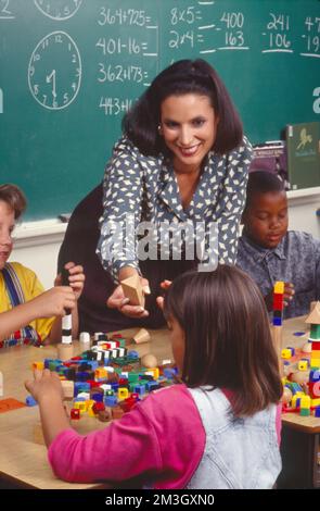 Hispanic elementary school teacher working with students building with toys Stock Photo