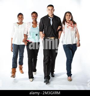 Teenage Students: Walking Forwards. Full length portrait of a diverse group of friends walking and looking towards the camera with confident smiles. Stock Photo