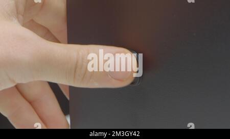 Close-up of pressing monitor start button. Action. Button for starting computer or electronic device. Finger presses computer power button. Stock Photo