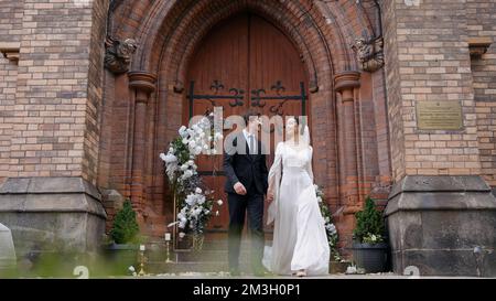 A bright and spectacular wedding couple. Action.Newlyweds where a bride in a white dress with a slit on her leg and a man with a beard in a suit walki Stock Photo