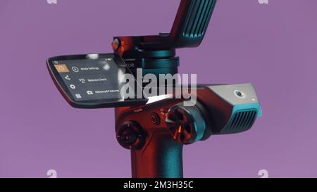 The concept of shooting with gadgets. Action.A large swivel tripod on which a large video camera is attached shoots in different directions on a brigh Stock Photo