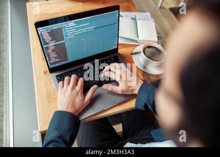 Back view of developer programmer freelancer working on project in cafe. Blurred background Stock Photo