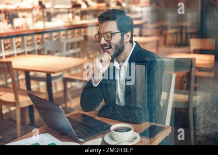 Focused indian businessman working on laptop in cozy cafe sitting near window Stock Photo