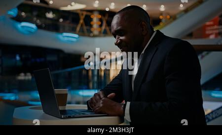 Middle-aged 50s ethnic man African worker manager typing wireless computer at table. Adult senior mature businessman working with laptop male Stock Photo