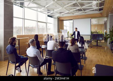 Team of people sitting at desks in office and having class with business teacher Stock Photo