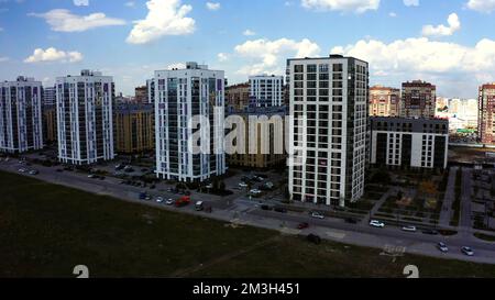 High-rise buildings view from a helicopter. Stock footage.Huge multi-colored residential complexes in a new area near shops,a road for cars and benche Stock Photo
