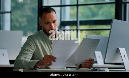 Pensive leader company CEO boss thinking African businessman manager auditor checking documents financial audit male worker busy with paperwork Stock Photo