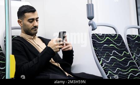 A man enjoying a ride. Media.A handsome man with stubble in office-style clothes rides a bus listening to music and sitting on the phone. High quality Stock Photo