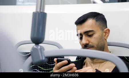A man enjoying a ride. Media.A handsome man with stubble in office-style clothes rides a bus listening to music and sitting on the phone. High quality Stock Photo