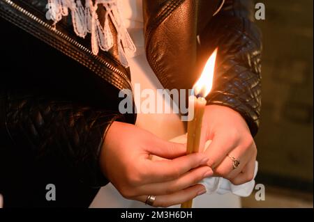 Man holding a burning candle in the dark with noise and grain effect, church candle. Stock Photo