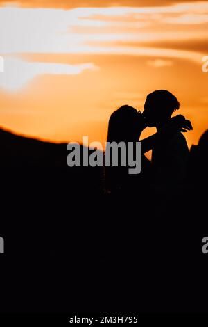 Silhouette of a couple kissing against a sunset sky Stock Photo - Alamy