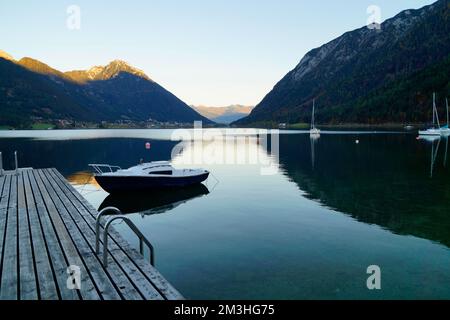 wooden pier and sailing boats resting on scenic calm alpine lake Achensee or Achen Lake in the Austrian Alps in Pertisau, Austria Stock Photo