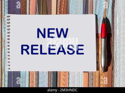 NEW RELEASE text on notepad with pen on vintage background Stock Photo