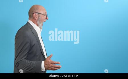 Emotional angry elderly man in profile on a blue background. copy space. banner Stock Photo