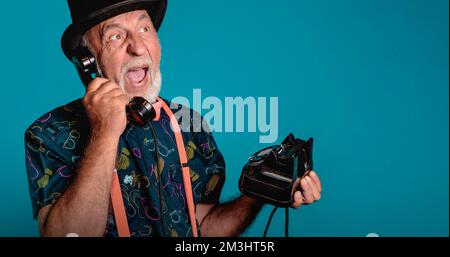 Emotional conversation on the phone. Banner with an elderly man on a blue background. Creative look. copy space Stock Photo