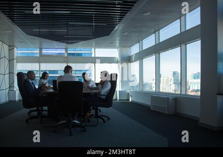 Silhouettes of people sitting at the table. Team of young business people working and communicating together in a modern office. Corporate team and Stock Photo