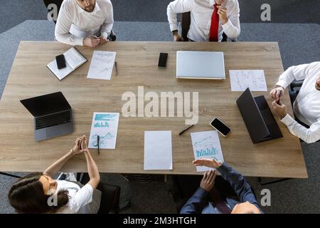 top view work workplace. A team of young office workers, businessmen with laptop working at the table, communicating together in an office. Corporate Stock Photo