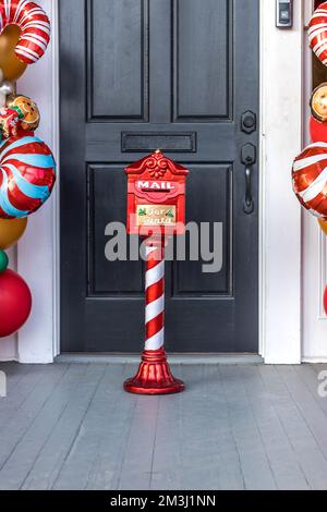 Decorative Christmas Santa Claus mailbox for letters from children outside a black exterior door with balloons