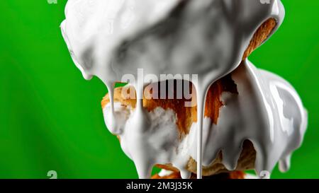 Trickling sweet white chocolate glaze covering small croissants on stick. Stock clip. Pastry products isolated on a green chroma key background Stock Photo