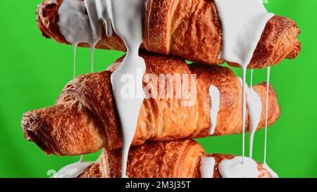 Concept of delicious breakfast. Stock clip. White glaze draining down the freshly baked croissants, close up view Stock Photo