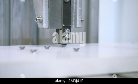 Machine twisting nails. Media. Close-up of automated machine twisting nails. Production machine that screws nails and bolts on boards. Stock Photo