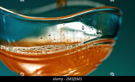 A bright glass with cognac. Stock clip.A large mug in which expensive whiskey is poured. High quality 4k footage Stock Photo