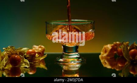A bright illuminated still life. Stock clip . A beautiful roomy mug in which brandy is poured and small oranges and tangerines lie next to it. High qu Stock Photo