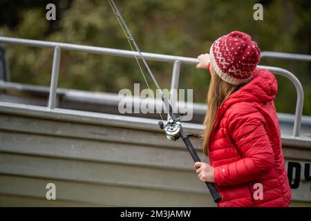 model girl fishing in a boat in summer in australia Stock Photo