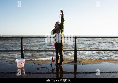 boy putting bait on a fishing rod for crabs by the ocean Stock Photo