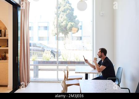 Mature man using mobile phone while having coffee in cafe Stock Photo