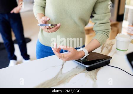 Midsection of female customer scanning smart watch on POS system Stock Photo