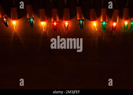 Christmas Lights. Retro light bulbs of different colors on dark wooden background with copy space Stock Photo