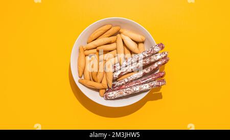 Top view of Spanish mini fuet and picos on yellow Stock Photo