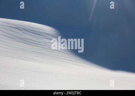 Aerial landscape of white snow forming a graphic texture, play of light and shadows forming beautiful line in the mountains Stock Photo