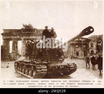 A Soviet heavy tank moving through Berlin, with the Brandenburg Gate in the background, May 1945.   Berlin fell to the Russian Army on 2nd May 1945, after a battle which lasted 17 days. Given the demeanour of the men riding on the tank, it is safe to assume that this photograph was taken after the German capitulation. Stock Photo