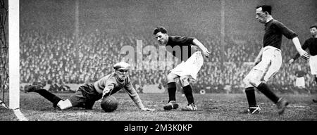 Photograph showing Dixon, the Stoke goalkeeper, attempting to save a shot from one of the Arsenal forwards, during the F.A. Cup Sixth Round match held at Highbury Stadium, 1928.  Unfortunately for Dixon, Arsenal emerged victorious from this match.     Date: 1928 Stock Photo