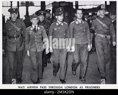 Three captured German aircrew (centre) being marched through a London train station by British military police, on their way to a prisoner-of-war camp.