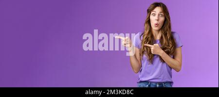 Amused surprised enthusiastic cute girlfriend wanna try advertising product folding lips excited look admiration excitement stand purple background Stock Photo
