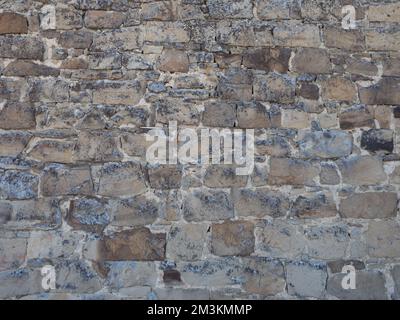 Close-up of light tan, taupe, and gray stones joined with mortar. The stones have lichen growing on them. Stock Photo