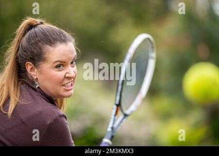female tennis player practicing forehands and hitting tennis balls on a grass court in england Stock Photo