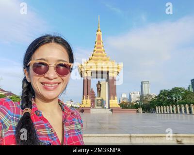 A young Asian tourist woman taking a selfie at the Statue of King Father Norodom Sihanouk Memorial in Phnom Penh city, Cambodia. Stock Photo