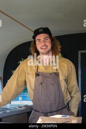 Happy confident young entrepreneur looking at camera, smiling male small cafe business owner employee standing in coffee shop, businessman wear apron Stock Photo